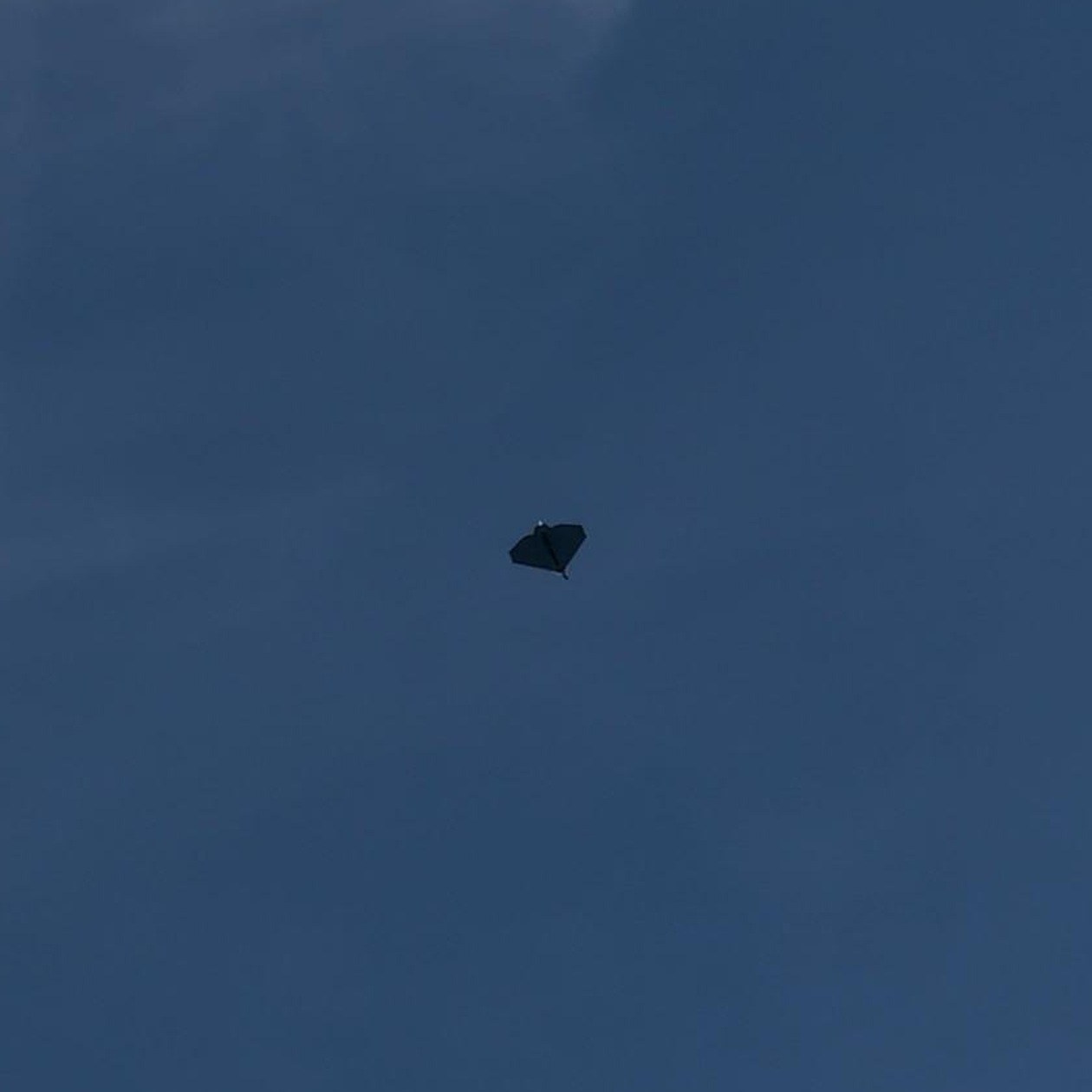 Dunkle Silhouette eines Flugobjekts in Nurflügelform am Himmel